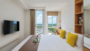 Ein Hotelzimmer mit Bett, Fernseher, Fenster mit Blick und einem Bücherregal.