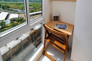 A room with a large window, a wooden desk, and a newspaper. - Good Deal And Homey Studio Apartment Tokyo Riverside Pik 2 (Jakarta)
