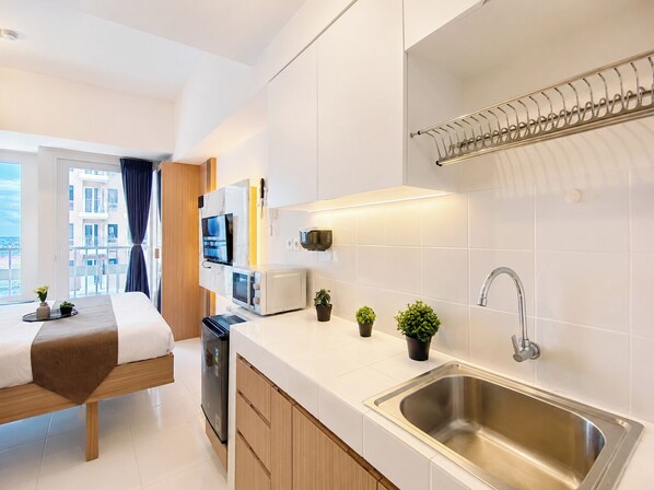 Eine moderne Küche mit integriertem Geschirrspüler, einer Edelstahl-Spüle und einem Fenster mit Blick auf eine Stadtlandschaft.