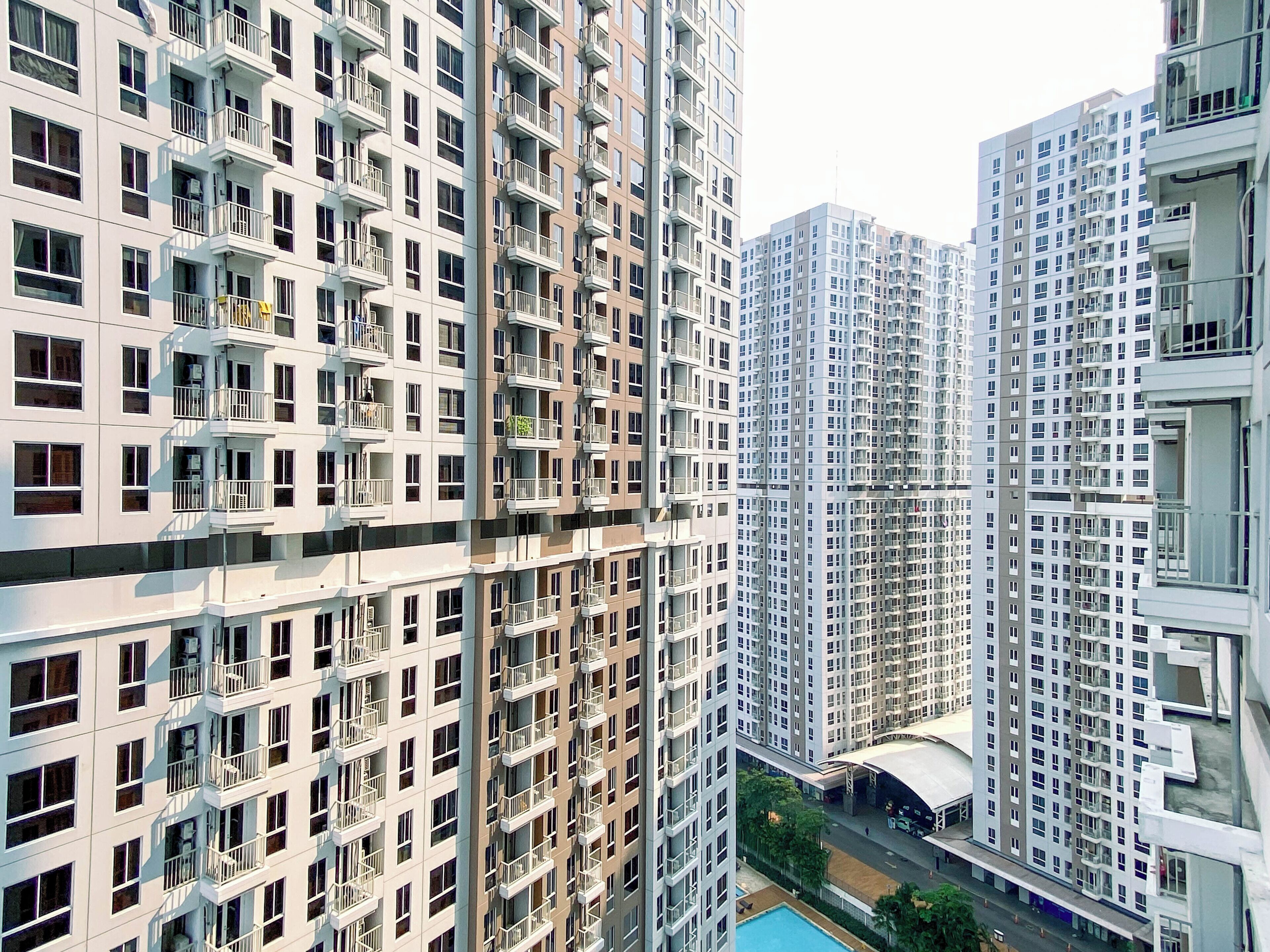 Um edifício residencial alto, com várias varandas, piscina e galeria coberta.