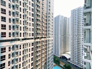 A high-rise residential building with multiple balconies, a swimming pool, and a covered walkway. - Stylish Bright Studio Apartment Tokyo Riverside (No Kitchen) (Teluknaga)
