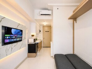 Eine moderne Küche mit Flachbildfernseher an der Wand, einer Mikrowelle und einem Spülbecken.
