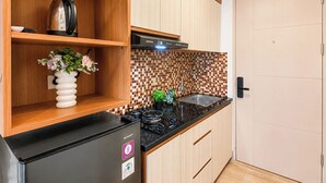 A kitchen with a black refrigerator, a stove, and a tiled backsplash. - Good And Cozy Studio At Apartment Tokyo Riverside Pik 2 (Jakarta)