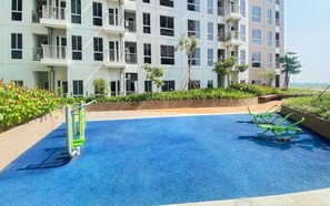 Une piscine à la surface bleue, entourée d’un petit muret et de verdure.