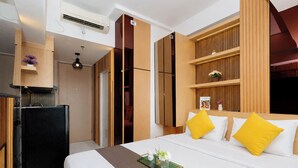 A hotel room with a bed, a desk, a wardrobe, and a kitchenette. - Warm Stylish Studio Apartment Tokyo Riverside Pik 2 (Jakarta)