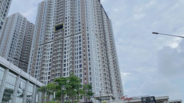 A high-rise residential building with multiple balconies, a modern glass facade, and a sign indicating a nearby university. - Warm Stylish Studio Apartment Tokyo Riverside Pik 2 (Jakarta)