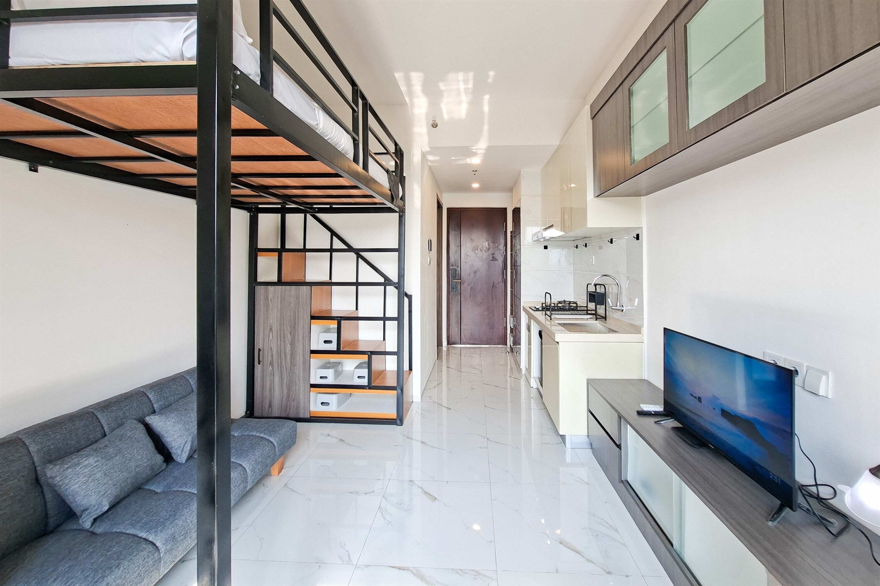 A modern apartment with a bunk bed, a sofa, a kitchen area, and a TV.