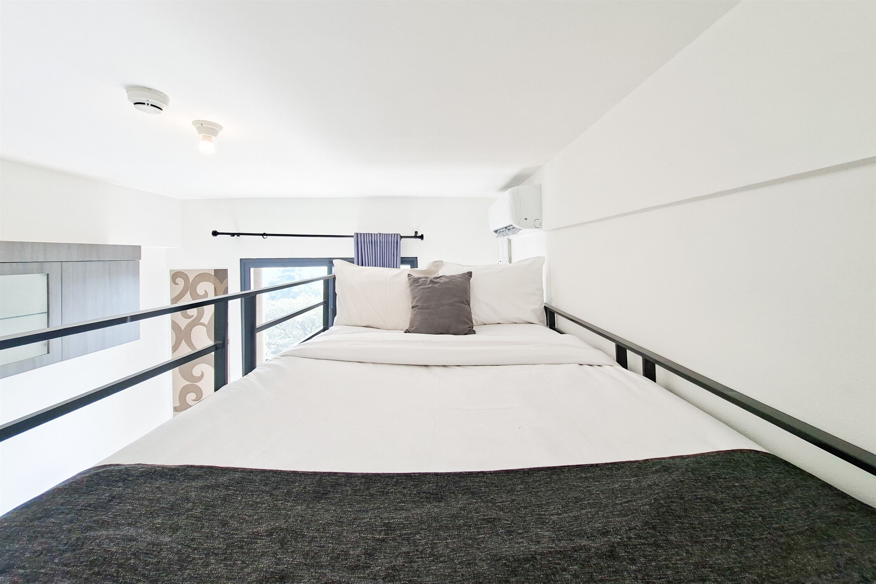 Una habitación de hotel moderna con una cama, un ventanal, un balcón y un ventilador de techo.