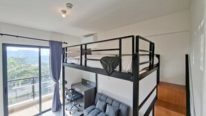 Camera moderna su più livelli con un letto a castello, una scrivania e un’area salotto accogliente.