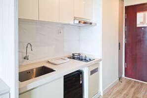 A compact kitchen with a built-in dishwasher, a stainless steel sink, and a gas stove. - Comfortable And Modern Studio Room At Apartment Sky House Bsd (Tangerang)