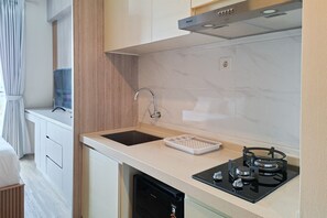 Een kleine keuken met een spoelbak, een kookplaat en een vaatwasser.