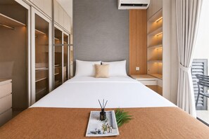 A hotel room with a large bed, a built-in wardrobe, a bedside table, and a window with curtains. - Comfortable And Modern Studio Room At Apartment Sky House Bsd (Tangerang)