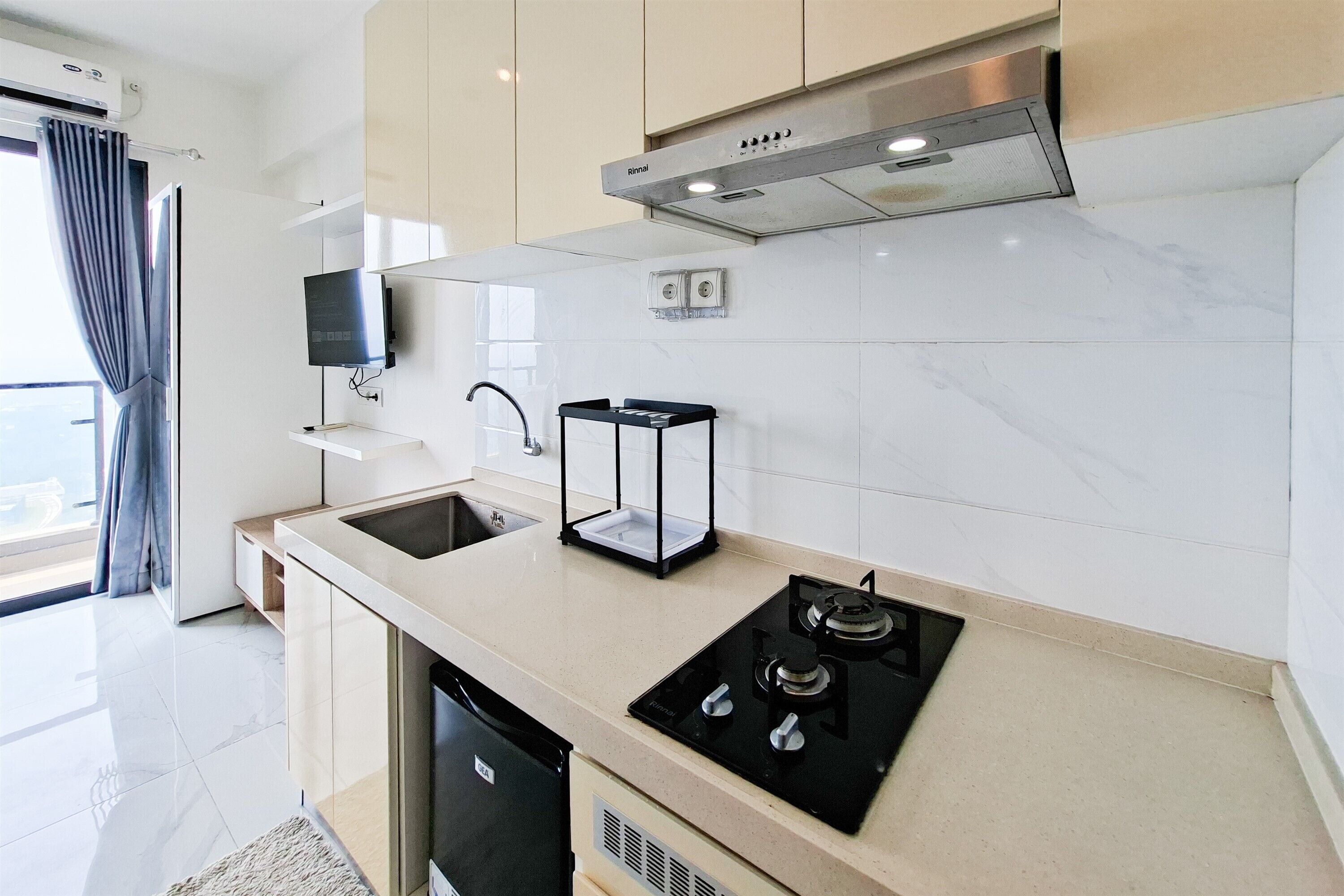 Uma cozinha moderna com fogão embutido, pia e TV de tela plana na parede.