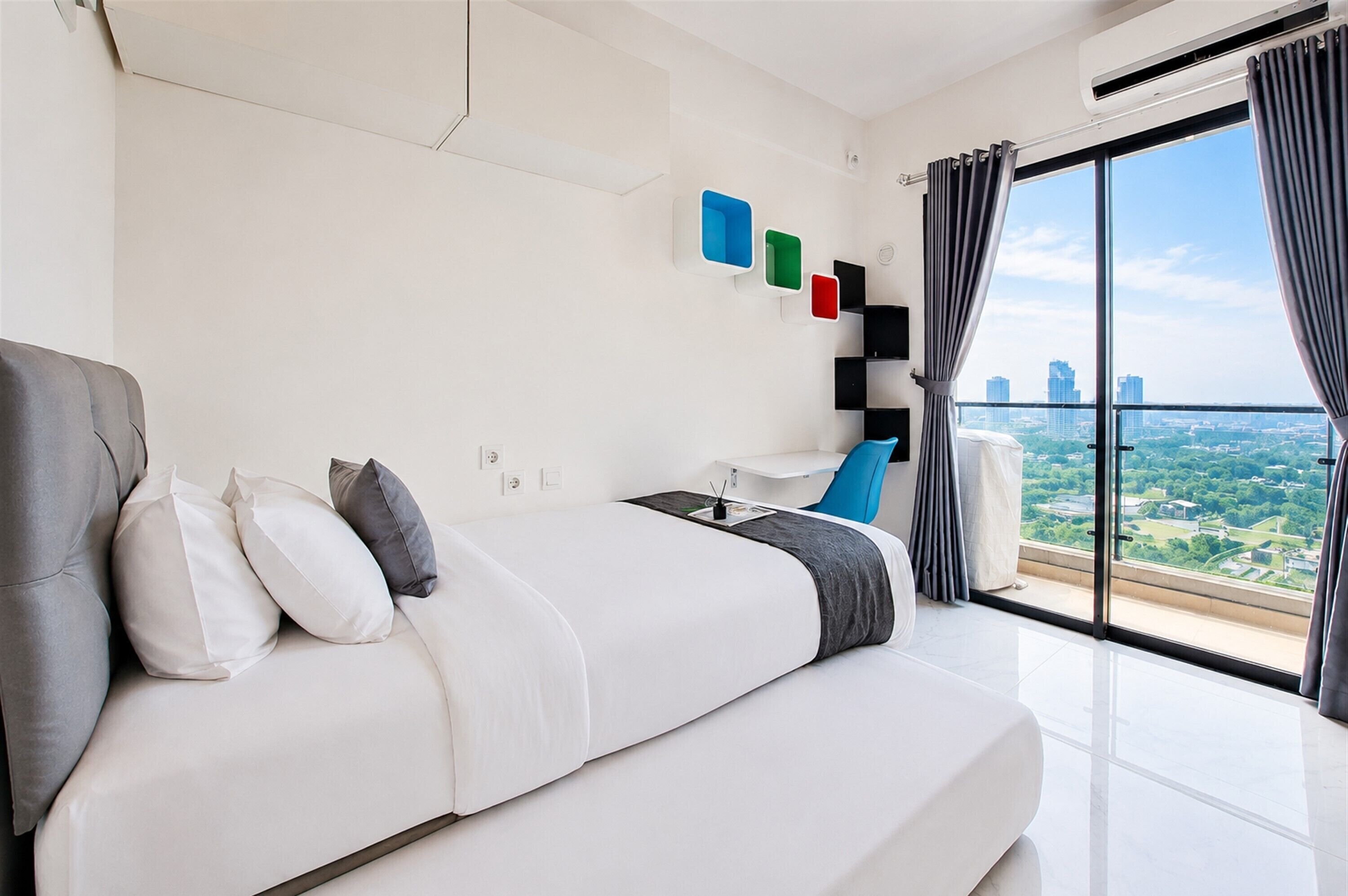 A modern hotel room with a large bed, a desk, and a view of the city.