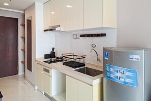 Una cocina compacta con un refrigerador de acero inoxidable, una estufa a gas y un lavamanos.