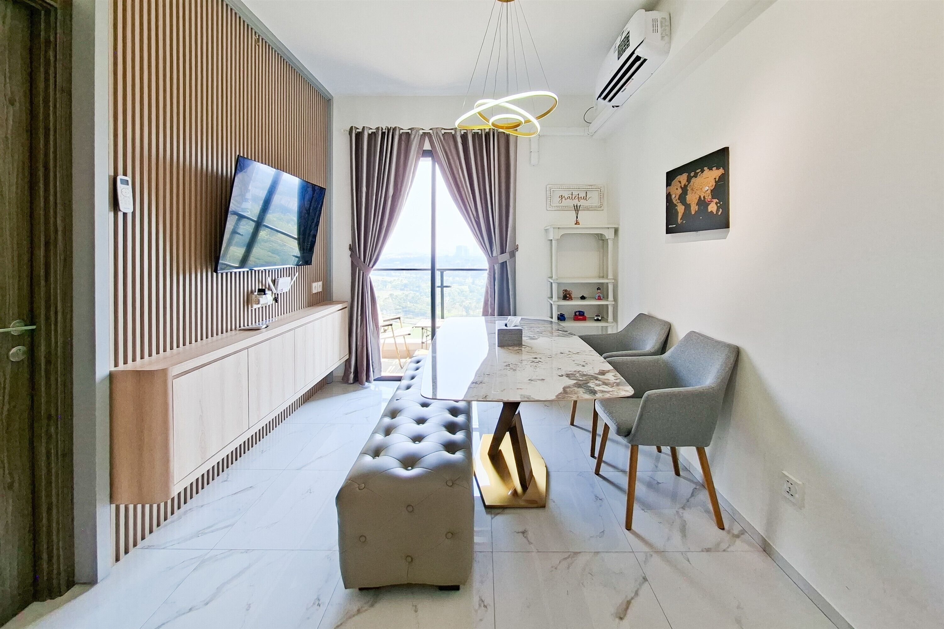 A modern living room with a flat-screen TV, a dining table, and a bench.