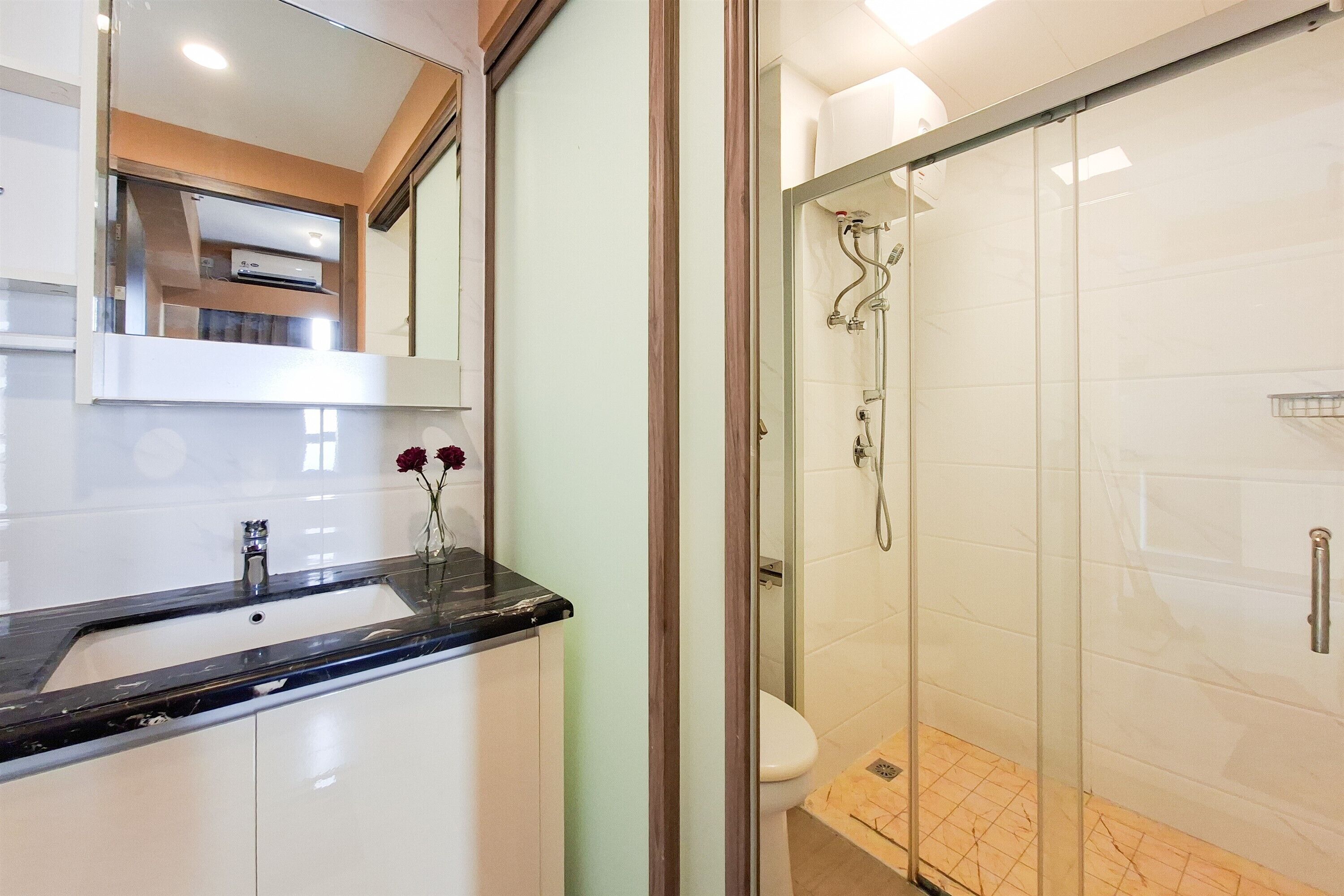 A bathroom with a glass-enclosed shower, a sink with a marble countertop, and a mirror above the sink.