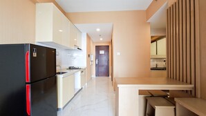 A modern kitchen with a black refrigerator, a wooden dining table, and a kitchen island. - Compact And Warm 2Br Apartment Sky House Bsd (Tangerang)