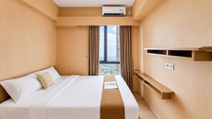 A hotel room with a bed, a window with curtains, an air conditioning unit, and a built-in shelf. - Compact And Warm 2Br Apartment Sky House Bsd (Tangerang)
