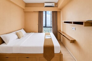 Ein Hotelzimmer mit Bett, Fenster mit Vorhängen, Klimaanlage und integriertem Regal.
