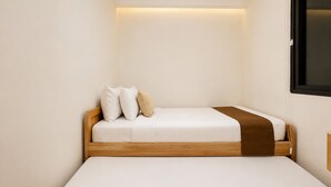 A small, single-bed room with a wooden headboard, a bedside table, and a wall-mounted TV. - Modern Comfy 2Br Sky House Bsd Apartment (Tangerang)