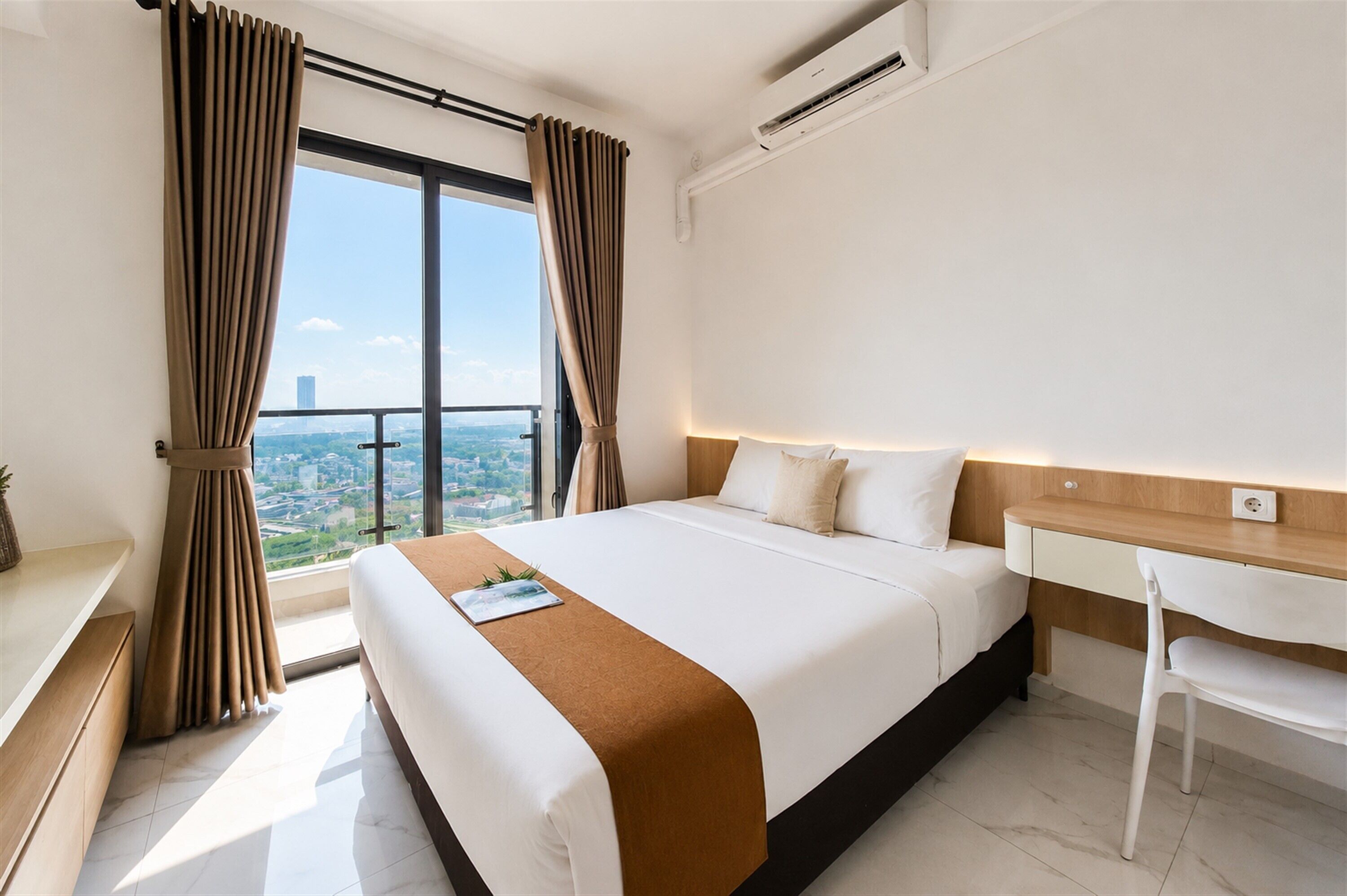 Habitación de hotel con una cama grande, un escritorio, una silla y vistas a la ciudad por la ventana.