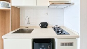 Een kleine keuken met een spoelbak, kookplaat en koffiezetapparaat.