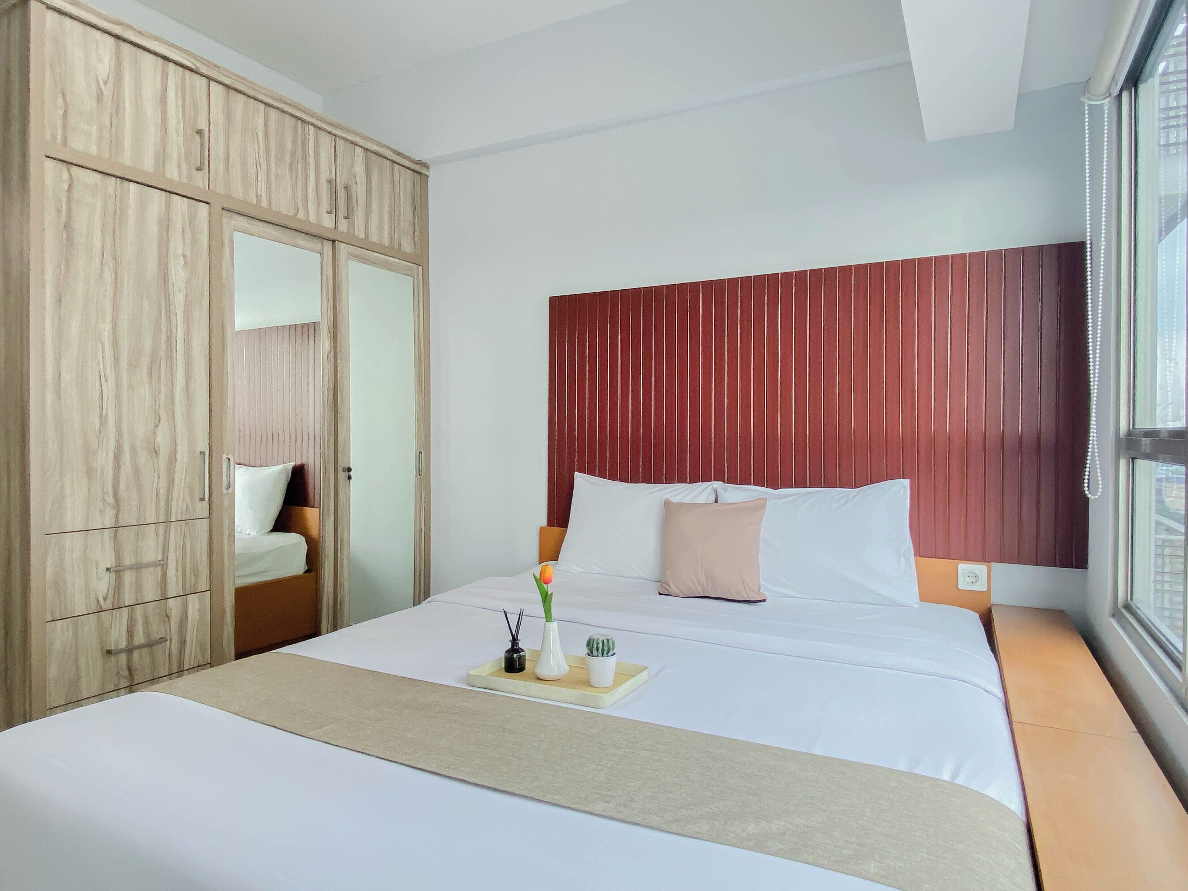 Une chambre d’hôtel avec un lit, une armoire en bois, une fenêtre donnant sur un beau paysage et une table de chevet avec un plateau.