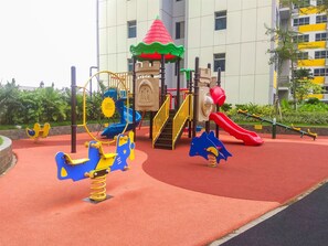 Une aire de jeux avec un toboggan, des balançoires et une structure d’escalade.
