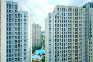 Un immeuble résidentiel de grande hauteur, doté de nombreux balcons et d’une piscine située dans la cour intérieure.