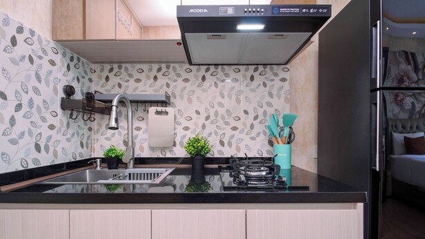 A modern kitchen with a black countertop, a built-in stove, a sink, and a stainless steel faucet. - Sophisticated Studio At Apartment Springlake Summarecon Bekasi (Bekasi)