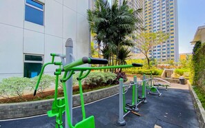 Des appareils de musculation en plein air, installés dans un espace aménagé, avec un bâtiment en arrière-plan.