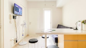 Eine moderne Küche mit flachbildschirmfernseher an der Wand, einer weißen Arbeitsplatte und zwei Barhocker.