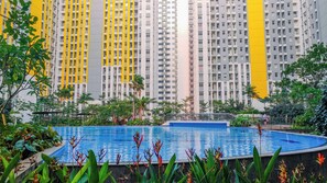 A residential building with a swimming pool surrounded by tropical plants. - Calming And Comfortable Living In 3Br At Apartment Springlake Summarecon Bekasi (Bekasi)