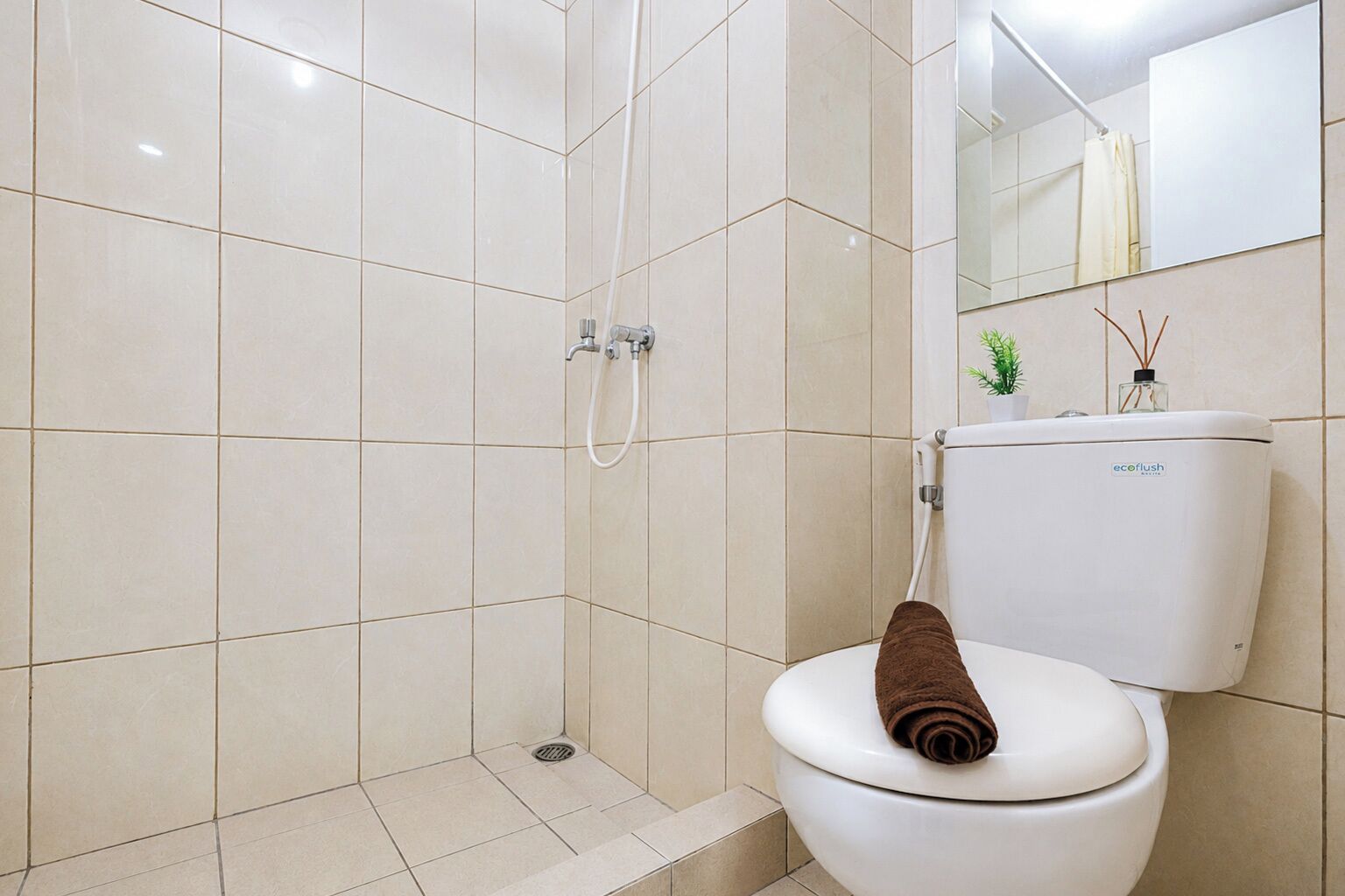 A bathroom with a shower, toilet, and a mirror.