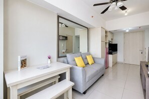 A modern living room with a grey sofa, a white coffee table, and a large mirror. - Compact With Minimalist Design 2Br At Springlake Summarecon Bekasi Apartment (Bekasi)