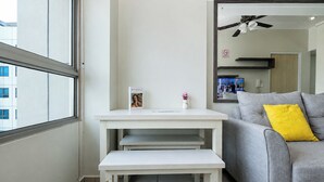 Ein modernes Wohnzimmer mit einem grauen Sofa, einem weißen Tisch und einem Fenster.