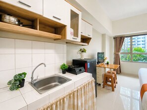 Une cuisine moderne avec un évier en acier inoxydable, des armoires en bois, un petit coin repas comprenant une table et des chaises, et une fenêtre avec des rideaux.