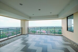 Ein geräumiger Balkon mit Fliesenboden und Geländer, der einen Blick auf die Stadt bietet.