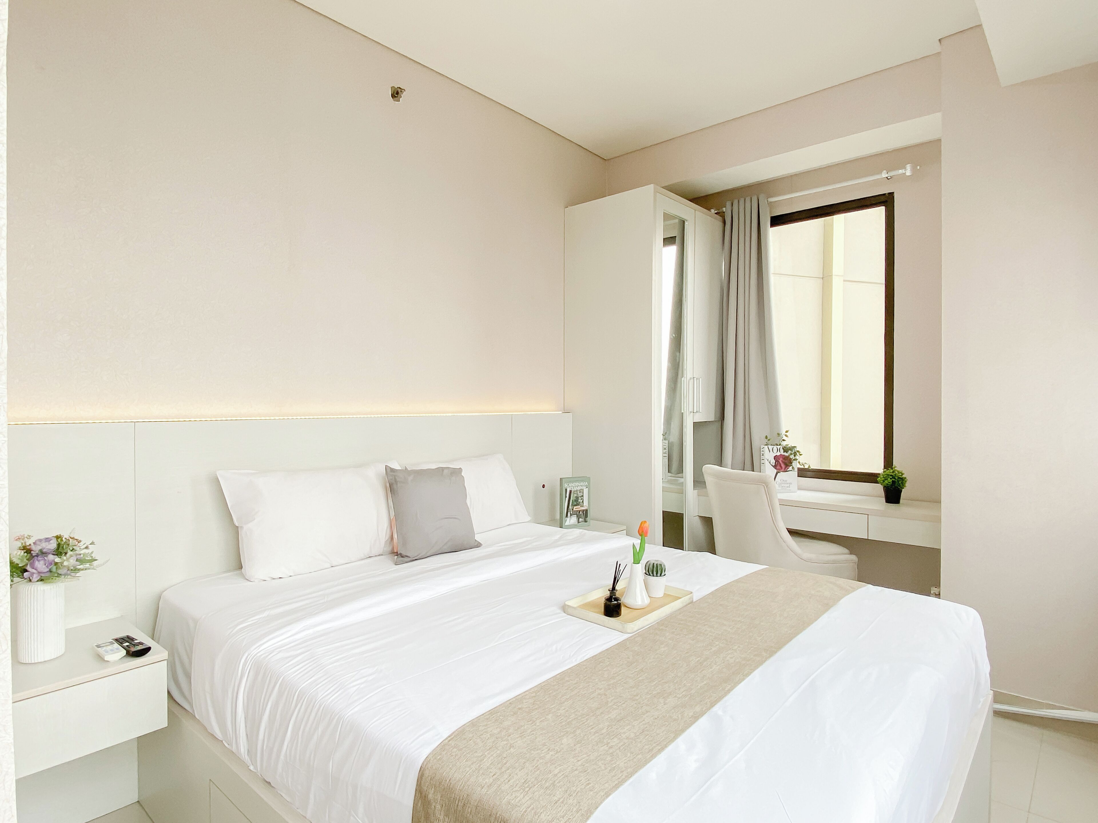 Una habitación de hotel con cama, mesita de noche, escritorio, silla y una ventana con cortinas.