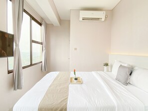 Ein Hotelzimmer mit einem Bett, einem Nachttisch mit einer Vase und einer Klimaanlage an der Wand.
