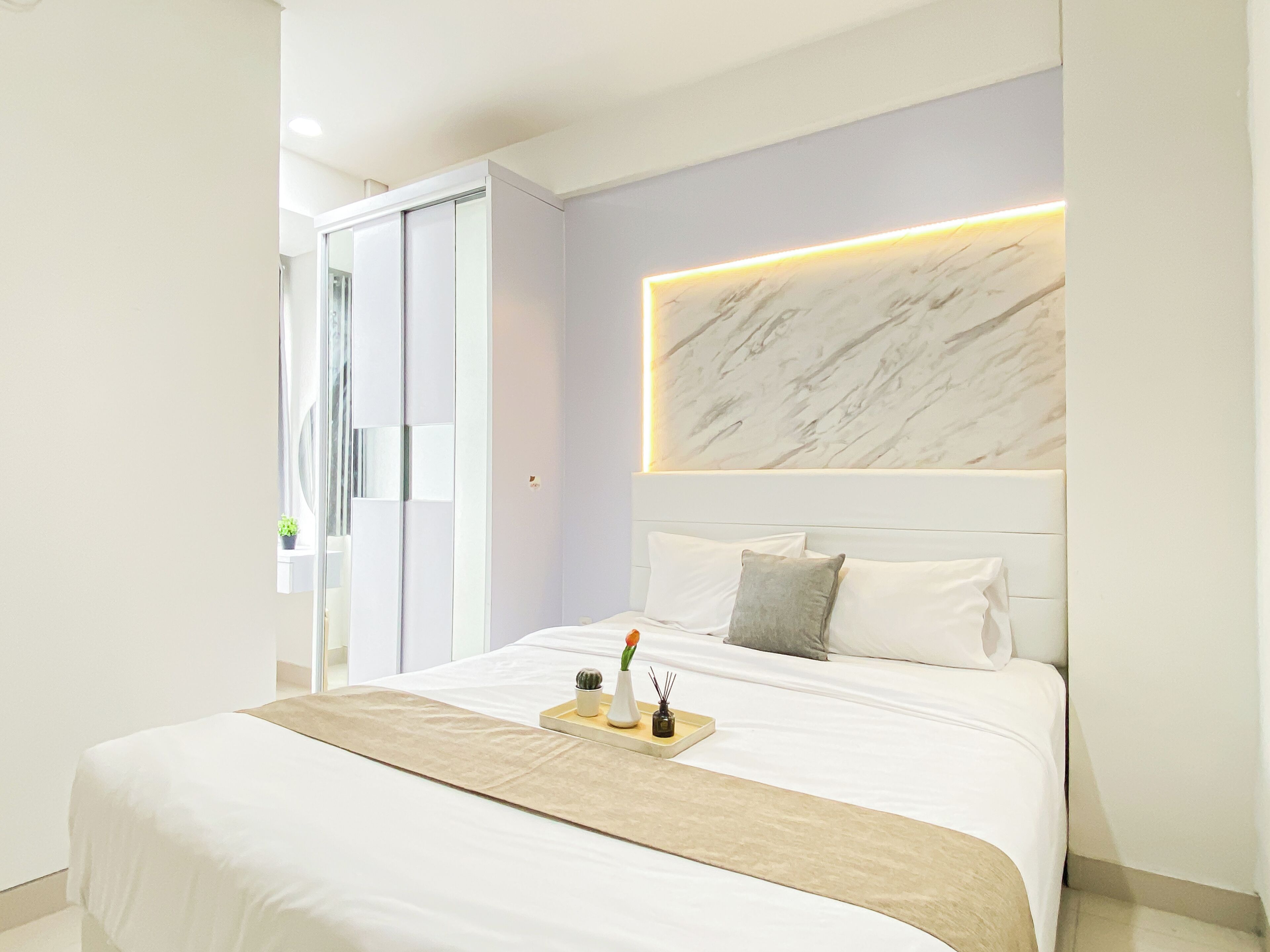A modern bedroom with a large bed, a marble headboard, and a bedside table with a tray.