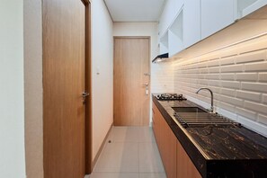 Eine schmale Küche mit einer Holztür, einer schwarzen Arbeitsplatte und einer gefliesten Spritzschutzwand.
