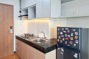 Eine kleine Küche mit einem Gasherd, einer Spüle und einem Kühlschrank, verziert mit verschiedenen Aufklebern.