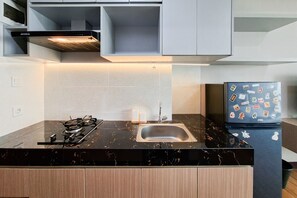 Eine moderne Küche mit einer schwarzen Marmorarbeitsplatte, einem Edelstahlspülbecken und einem Kühlschrank mit Magneten.