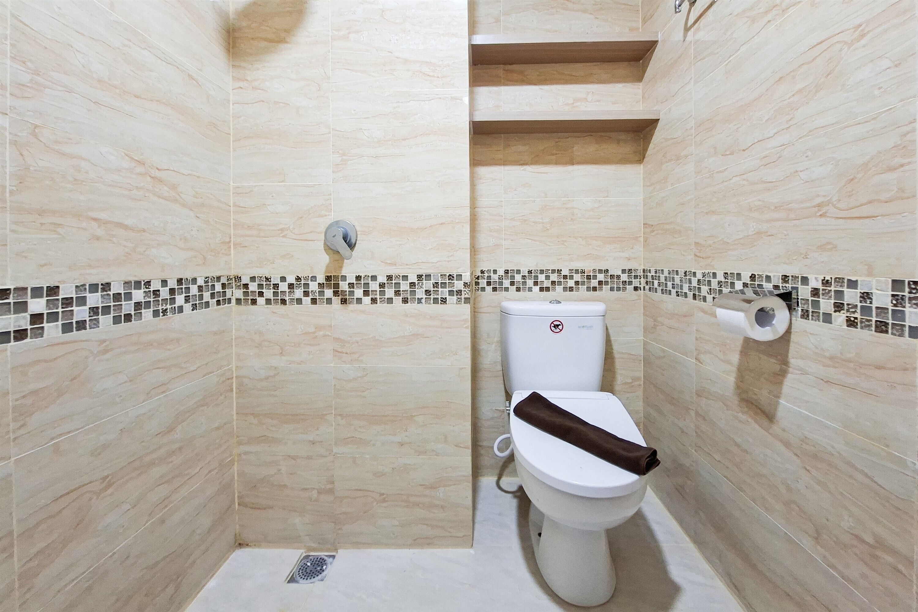 A bathroom with a toilet, a shower, and a tiled floor.