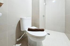 A bathroom with a toilet, a shower area, and tiled walls. - Enjoy Living Studio At Apartment B Residence (Tangerang)