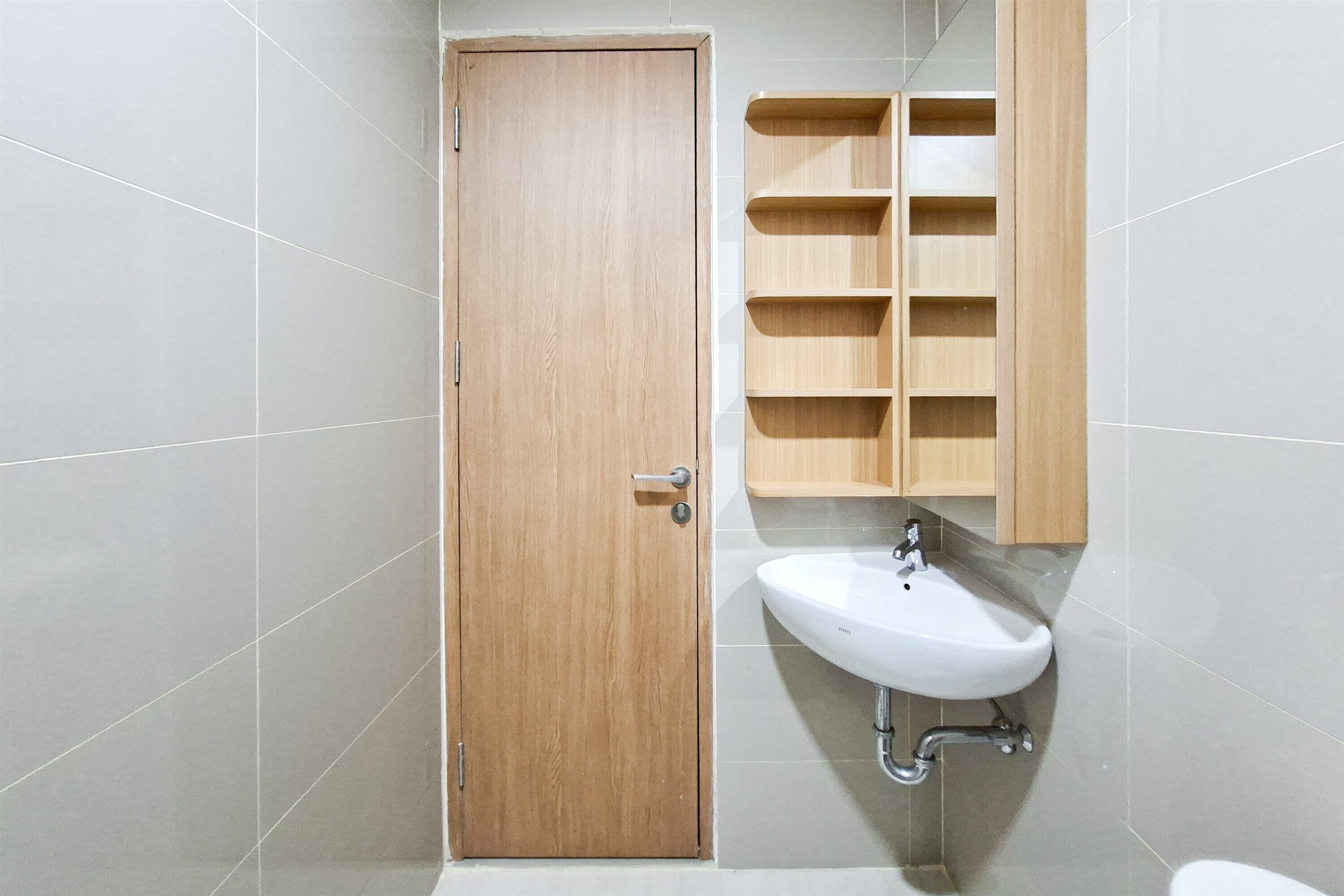 Een badkamer met een houten deur, een witte wastafel en een houten medicijnkastje.