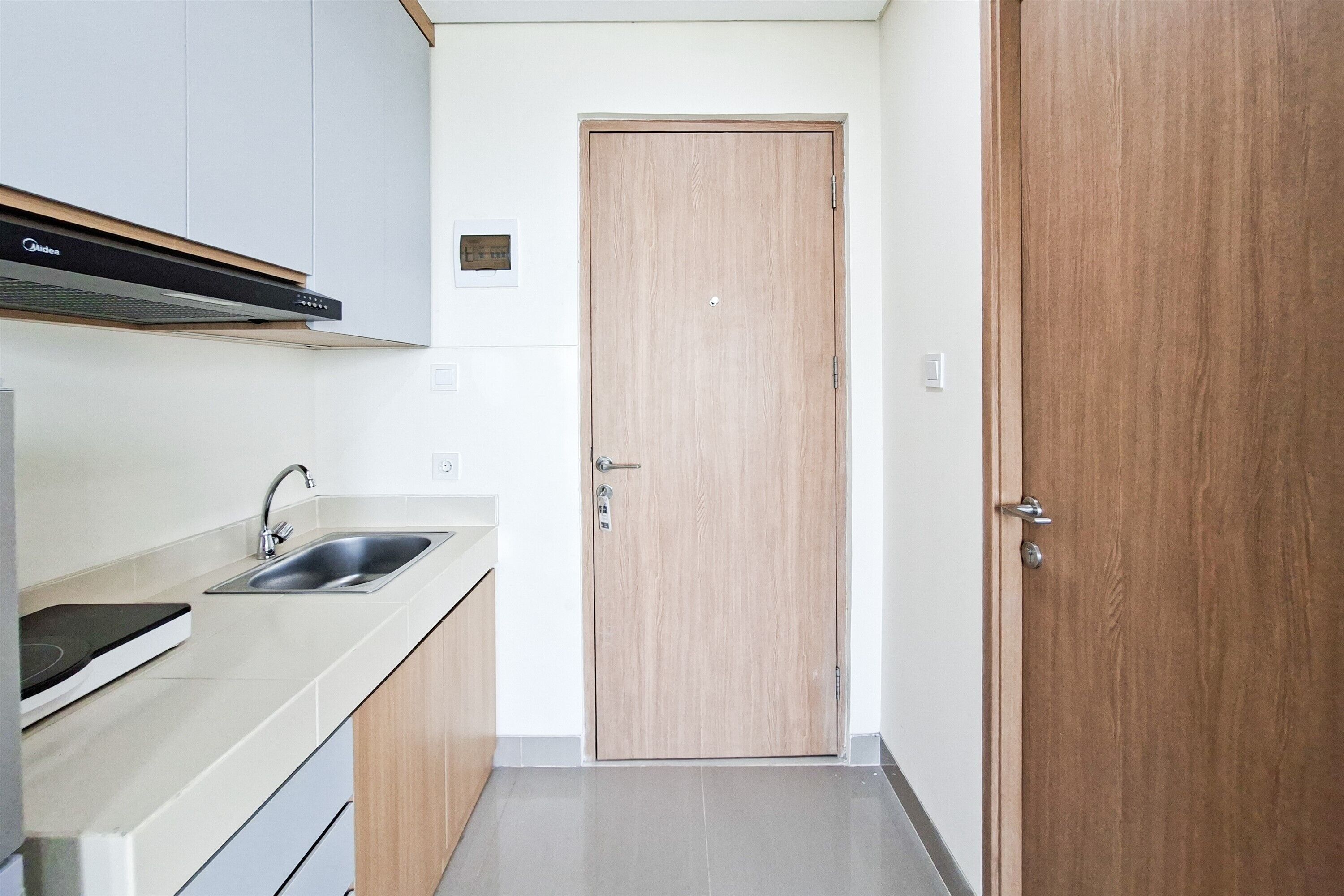 A kitchen with a sink, a stove, and a wooden door.