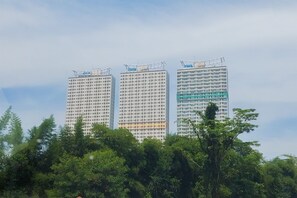 Three high-rise buildings with a dense arrangement of windows and a green facade on the right. - Splendid Studio At Apartment B Residence (Tangerang)